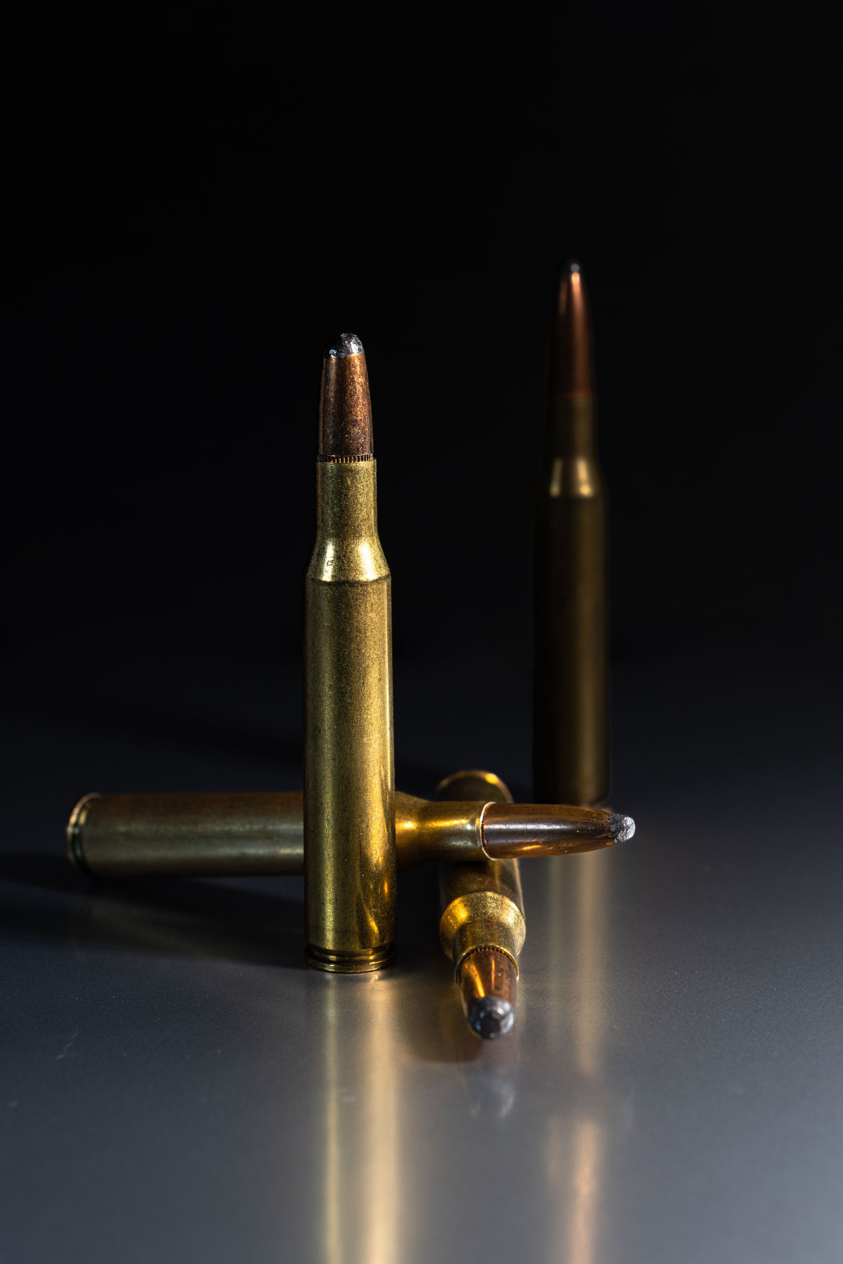 Detailed shot of rifle bullets standing on a reflective surface, showcasing metallic textures.